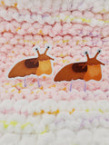 3inch sticker of a cartoon-style happy light brown slug and a 3inch textured sticker of a cartoon-style happy light brown slug.